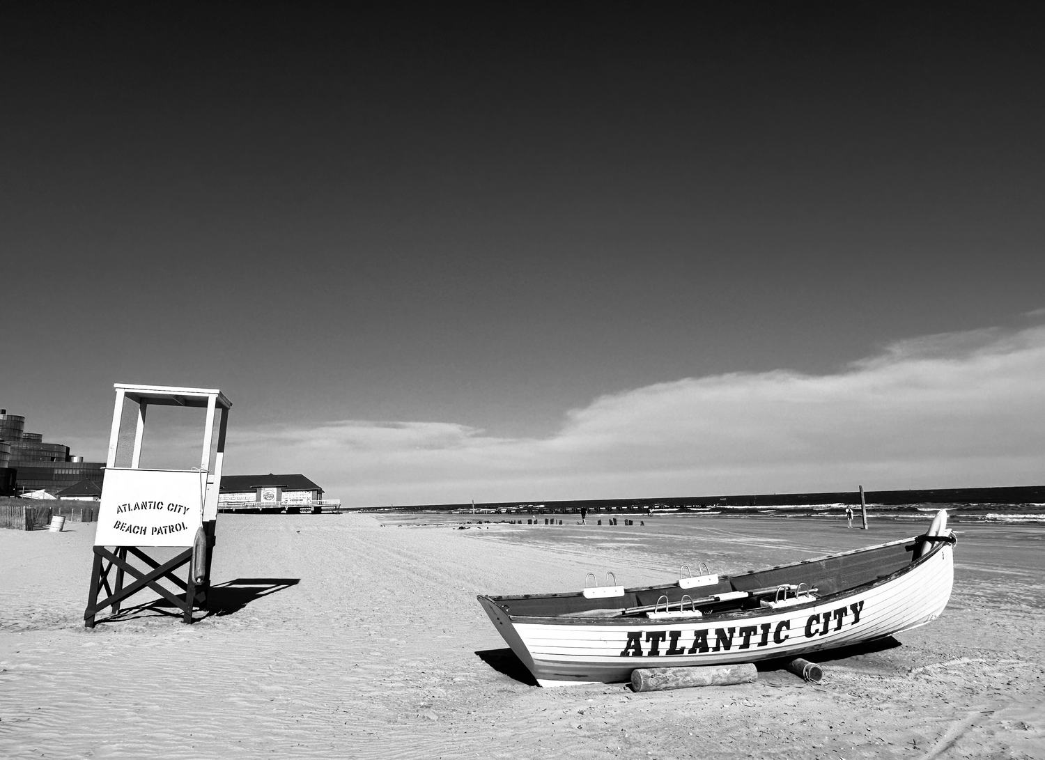 A beach patrol lifeboat and empty lifeguard stand on wide winter sand.