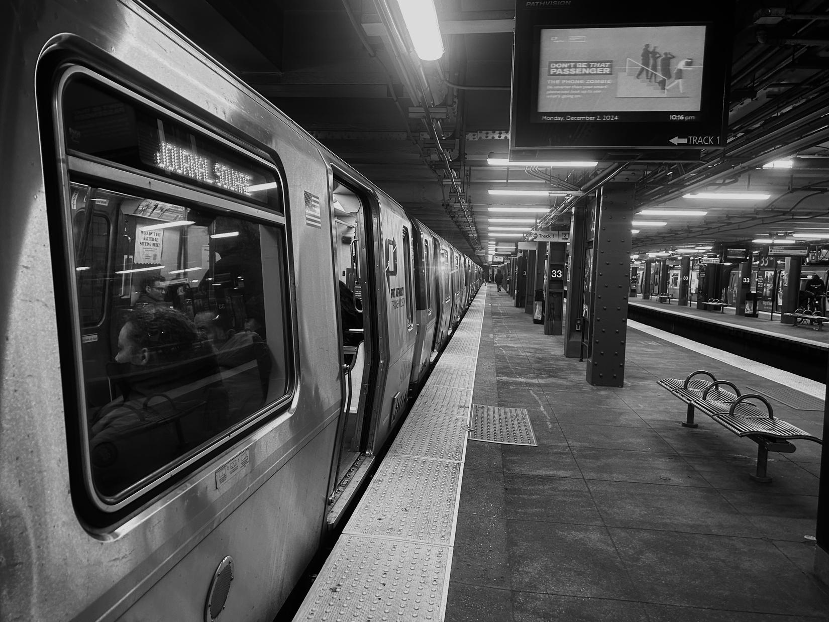 A PATH train at an empty platform, the concourse receding into the distance.