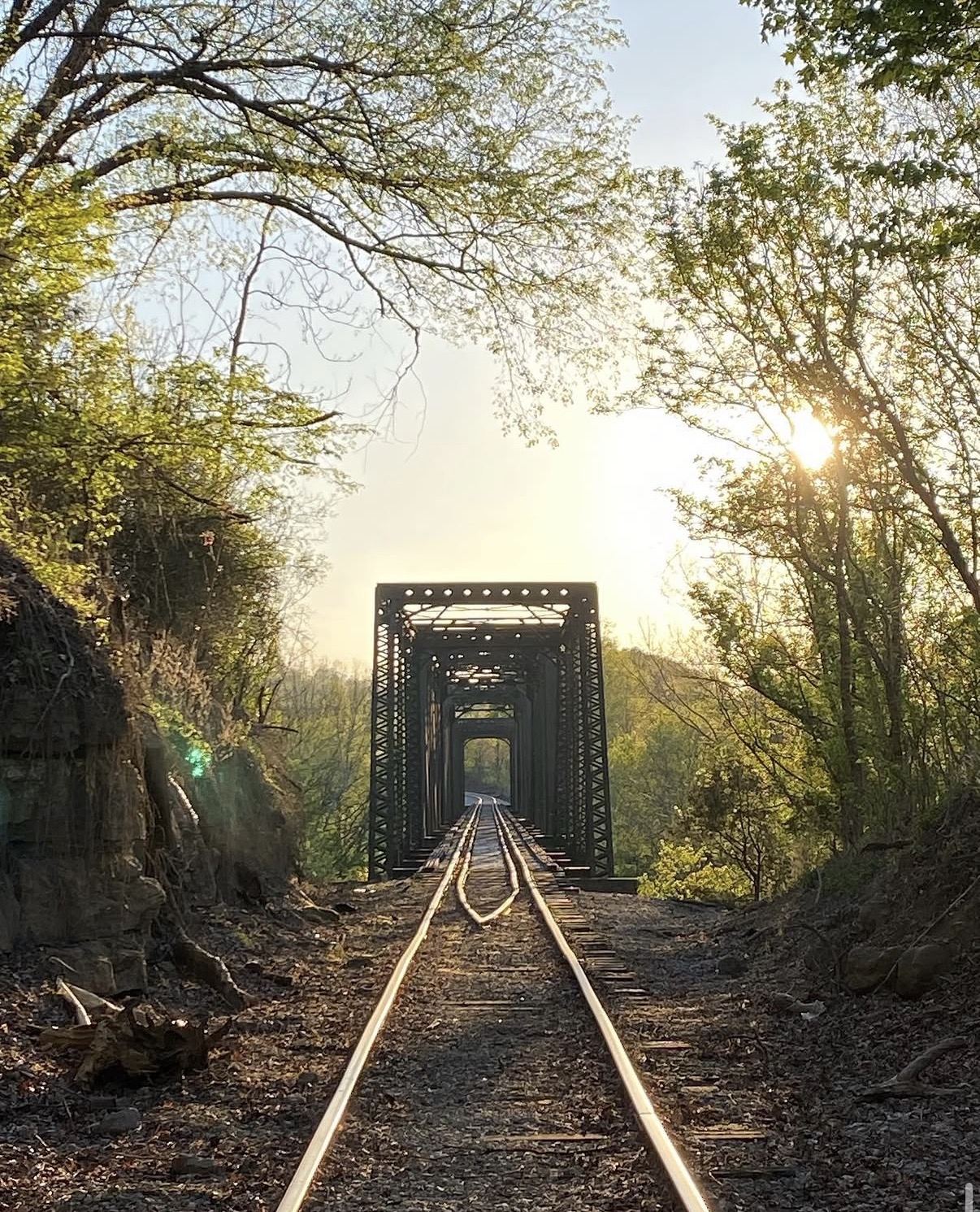 Railway track running toward a steel trestle bridge at sunrise.